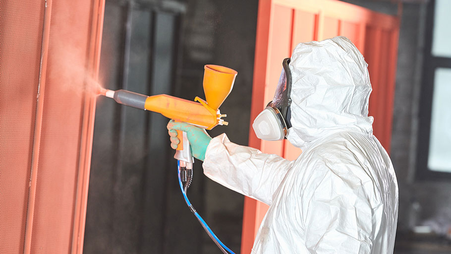 a worker powder coating a steel container