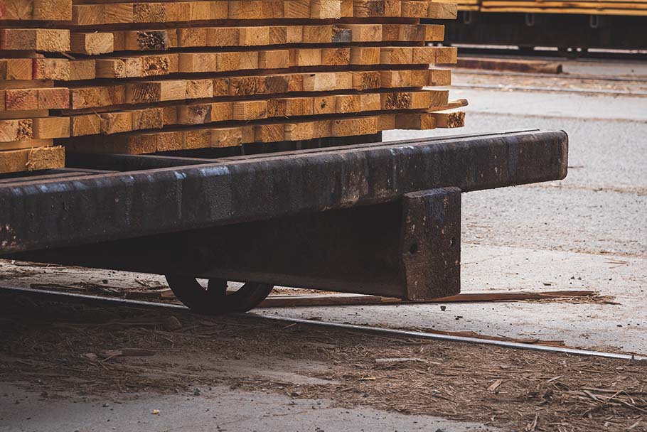 Un chariot de séchage chargé de bois se trouve sur un rail entouré de bran de scie et de débris de bois