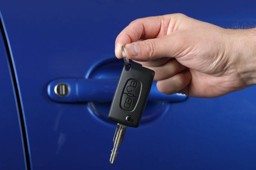 car key in hand on car door background