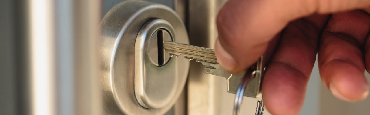 man is putting key into a door lock