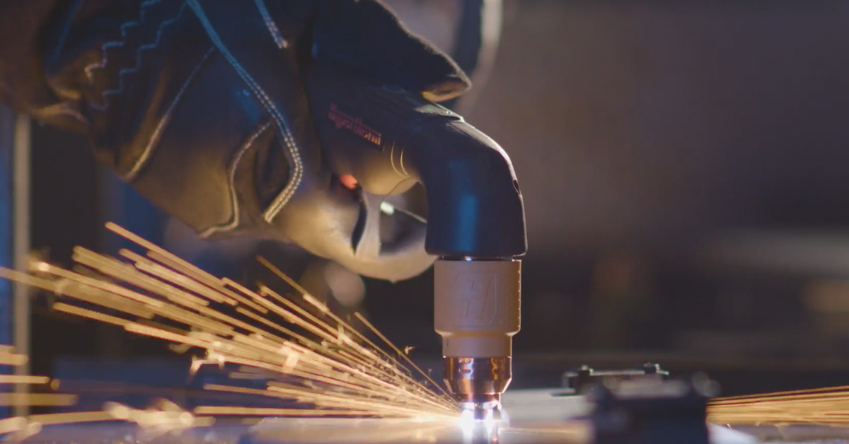 close up of a worker cutting metal with a plasma cutter